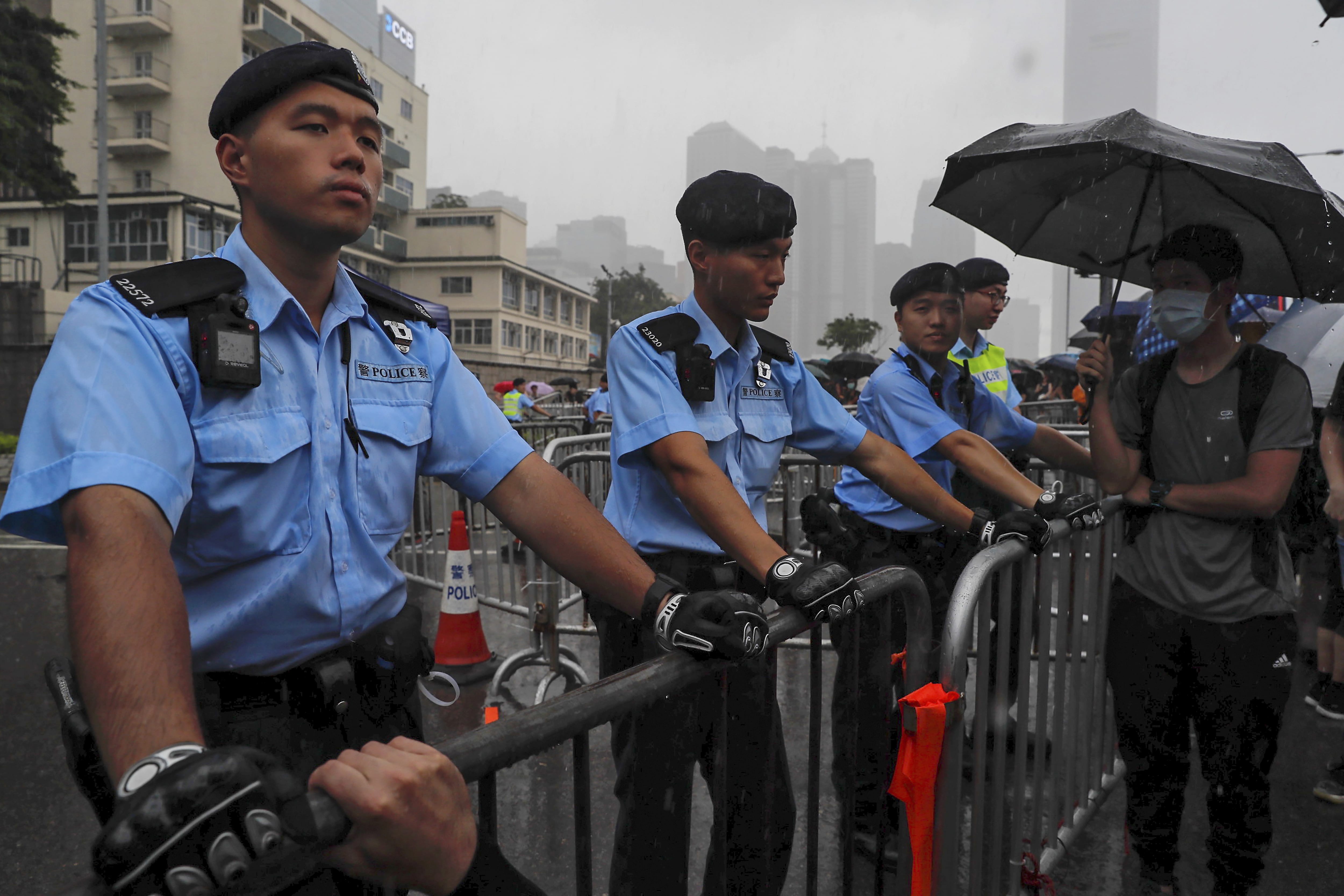 Policemen stand guard in the rain as protesters gather near the Legislative Council continuing protest against the unpopular extradition bill in Hong Kong, Monday, June 17, 2019. A member of Hong Kong's Executive Council says the city's leader plans to apologize again over her handling of a highly unpopular extradition bill.