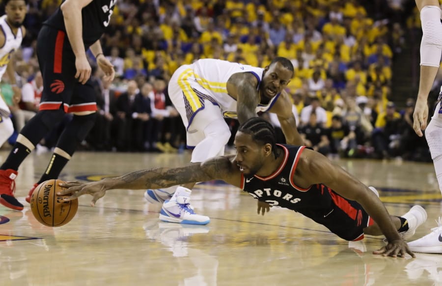 Toronto Raptors forward Kawhi Leonard, foreground, reaches for the ball in front of Golden State Warriors forward Andre Iguodala during the first half of Game 3 of basketball’s NBA Finals in Oakland, Calif., Wednesday, June 5, 2019.