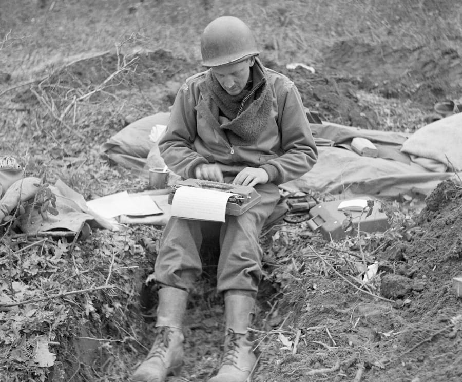FILE - In this February 1944, file photo, Don Whitehead, Associated Press correspondent, writes his story of the landing at Anzio Beach in Italy, from a fox hole. Whitehead, known by his colleagues as “Beachhead Don,” returned to Normandy for the tenth anniversary of the D-Day invasion, June 5, 1954, which he covered when he followed the 1st Infantry Division onto Omaha Beach.