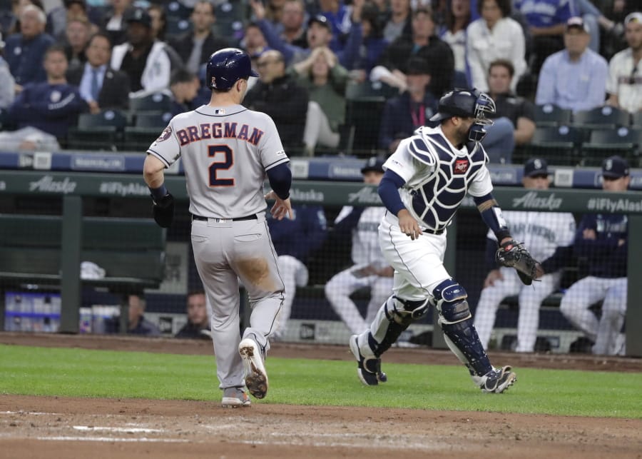 Houston Astros’ Alex Bregman (2) crosses the plate to score on a fielder’s choice ball hit by Yuli Gurriel after Seattle Mariners catcher Omar Narvaez, right, was out of position for the throw home by Mariners’ shortstop Dylan Moore during the sixth inning of a baseball game, Monday, June 3, 2019, in Seattle. (AP Photo/Ted S.