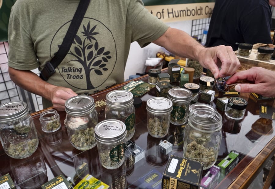 In this Thursday, June 20, 2019 photo a vendor with Talking Trees Farms a Northern Humboldt County sustainable cannabis farm, offers a taste of their latest crop of crafted marijuana flower to an attendee in the farmers market during a business to business networking event, WeedCon West 2019 in Los Angeles. Marijuana shoppers are going to be getting a message from California regulators: Go legal.