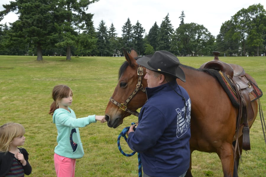 Emmalynn Covey, 10, of Portland taps a horse at Get Outdoors Day at Fort Vancouver National Historic Site. Get Outdoors Day, which is held at various sites nationally, is focused on promoting outdoor activities.