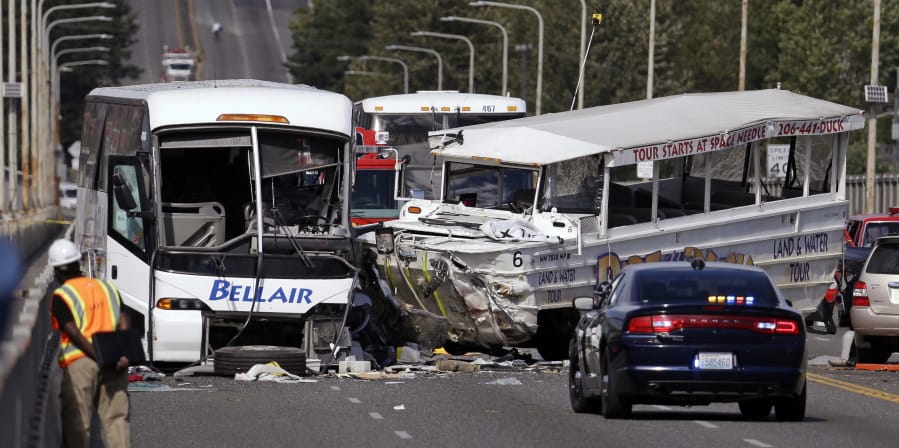 A “Ride the Ducks” amphibious tour bus, right, and a charter bus remain at the scene of a multiple fatality collision on Sept. 24, 2015, on the Aurora Bridge in Seattle.