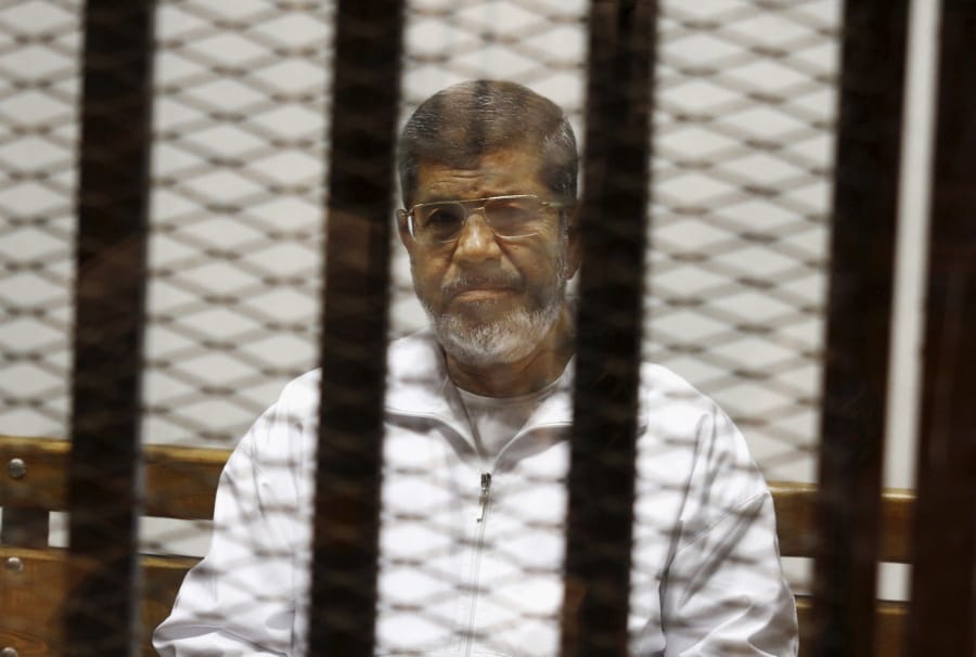 FILE - In this May 8, 2014 file photo, Egypt’s ousted Islamist President Mohammed Morsi sits in a defendant cage in the Police Academy courthouse in Cairo, Egypt. On Monday June 17, 2019, Egypt’s state TV said the country’s ousted President Mohammed Morsi, 67, collapsed during a court session and died. It said it occurred while he was attending a court trial on espionage charges. Morsi, who hailed from Egypt’s largest Islamist group, the now outlawed Muslim Brotherhood, was elected president in 2012 in the country’s first free elections following the ouster the year before of longtime leader Hosni Mubarak.