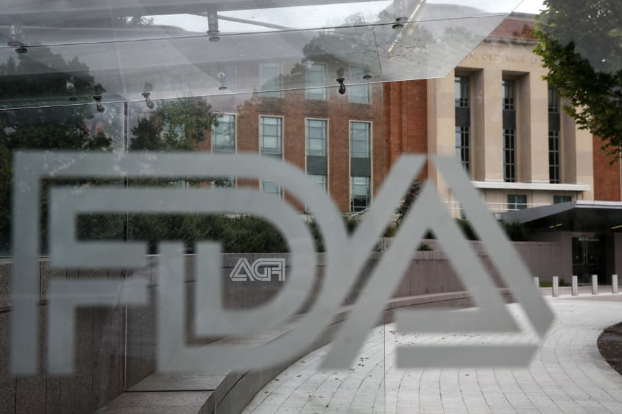 FILE - This Thursday, Aug. 2, 2018, file photo shows the U.S. Food and Drug Administration building behind FDA logos at a bus stop on the agency’s campus in Silver Spring, Md. The Food and Drug Administration’s first broad testing of food for a worrisome class of nonstick, stain-resistant industrial compounds found high levels in some grocery store meats and seafood and in off-the-shelf chocolate cake, according to unreleased findings FDA researchers presented at a scientific conference in Europe.