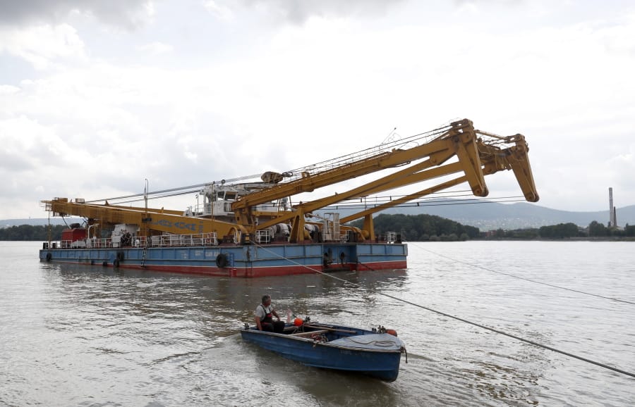 A floating crane able to lift 200 tons and which would be able to hoist the boat out of the water on its way on the site of the accident where a sightseeing boat capsized in Budapest, Hungary, Wednesday, June 5, 2019. South Korean officials say divers in Budapest have begun preparing a sunken tour boat in the hope that a huge floating crane can lift it out of the Danube River.