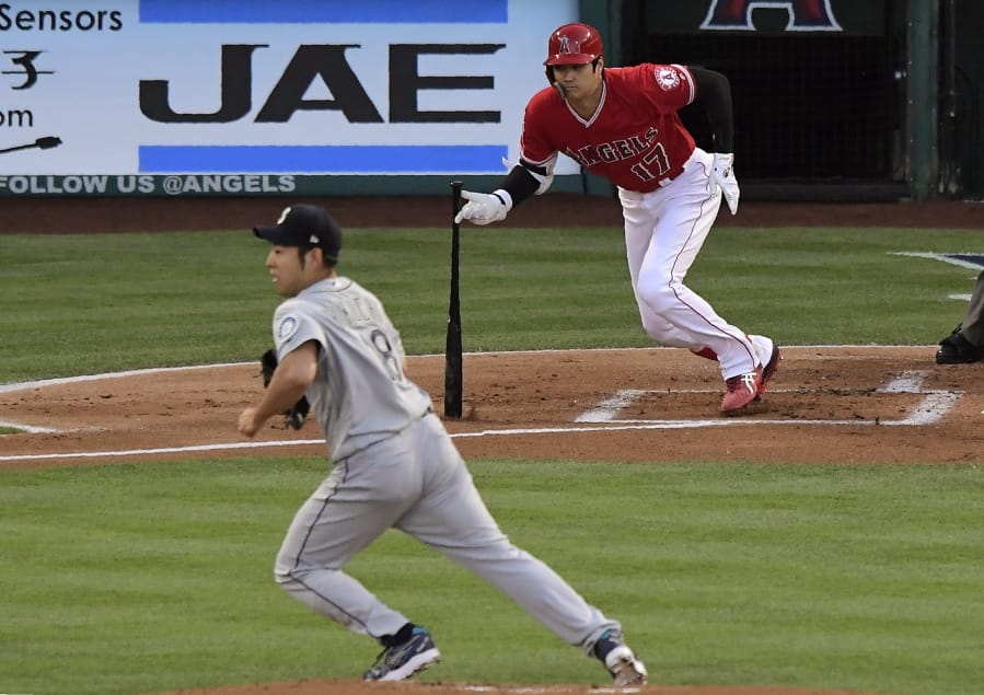 Los Angeles Angels’ Shohei Ohtani, right, runs to first for a single as Seattle Mariners starting pitcher Yusei Kikuchi runs to back up the first baseman during the first inning of a baseball game Saturday, June 8, 2019, in Anaheim, Calif. (AP Photo/Mark J.