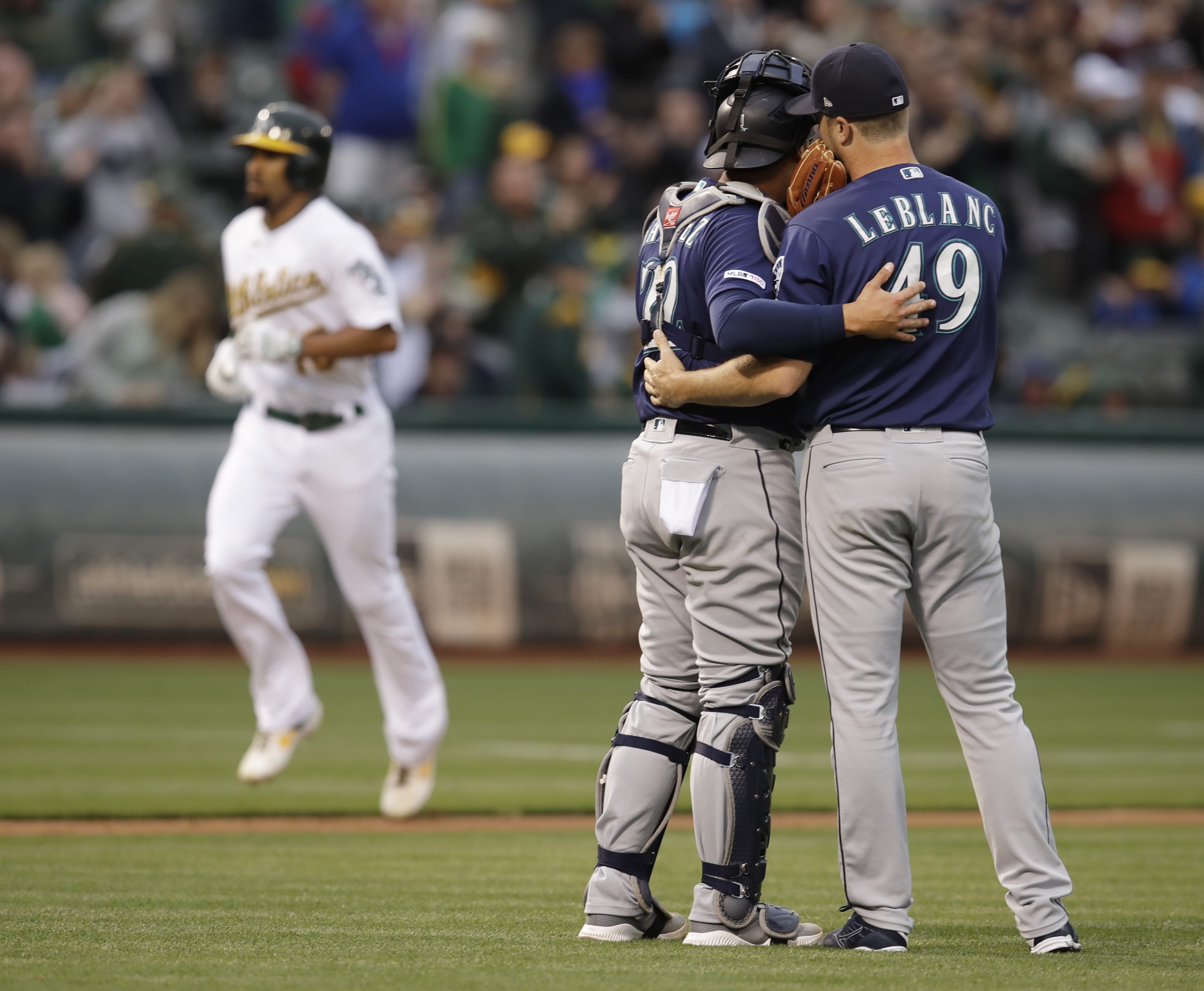 Seattle Mariners pitcher Wade LeBlanc, right, speaks with catcher Omar Narvaez as they wait for Oakland Athletics' Marcus Semien, back left, to run the bases after hitting a home run in the second inning of a baseball game Saturday, June 15, 2019, in Oakland, Calif.