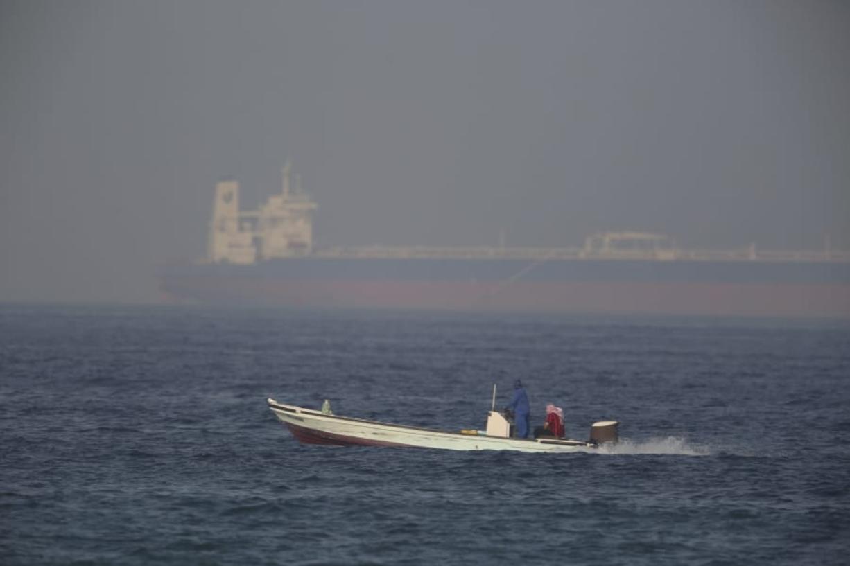 A fishing boat speeds past an oil tanker in the distance in Fujairah, United Arab Emirates, Saturday. The Kokuka Courageous, one of two oil tankers targeted in an apparent attack in the Gulf of Oman, was brought to the United Arab Emirates’ eastern coast Saturday.