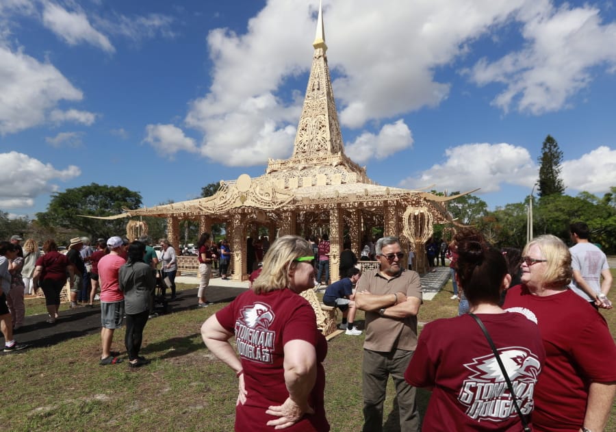 FILE - In this Feb. 14, 2019, file photo, people gather around the “Temple of Time” in honor of the 17 that were killed during the Marjory Stoneman Douglas High School shooting in 2018 in Coral Springs, Fla. The temple built as a memorial to the 17 victims of a Florida high school mass shooting is to be burned to the ground in a symbolic gesture of healing.
