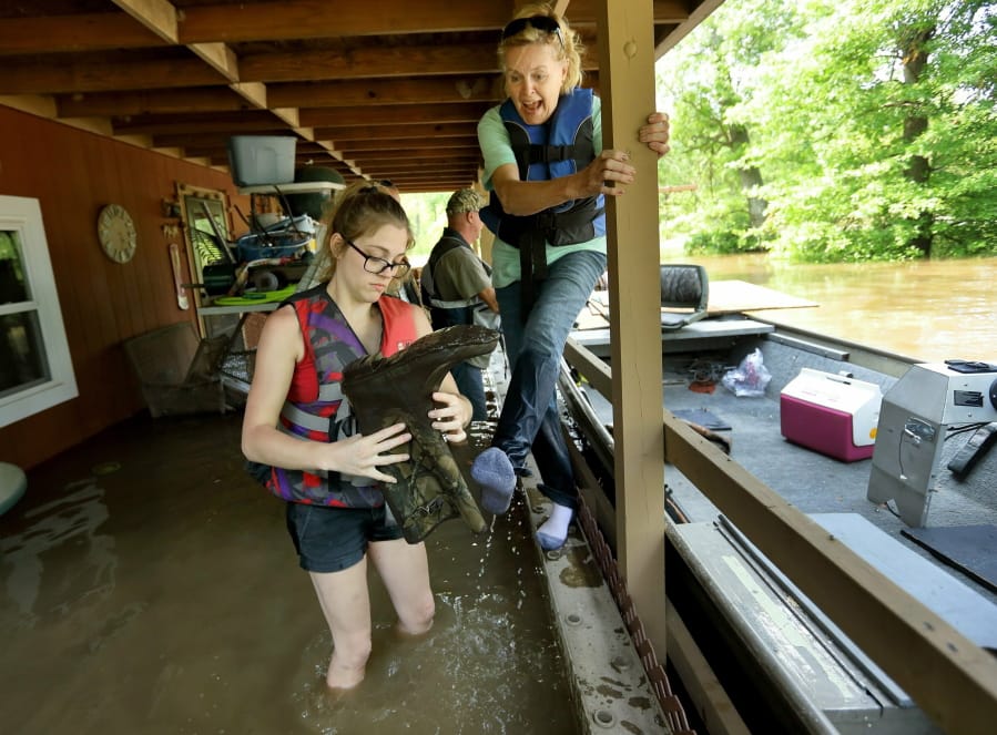 Emily Kientzel pours water from her grandmother Joan FitzGerald’s boot as they check on the home of a friend Sunday outside of Portage des Sioux, Mo. David Carson/St.