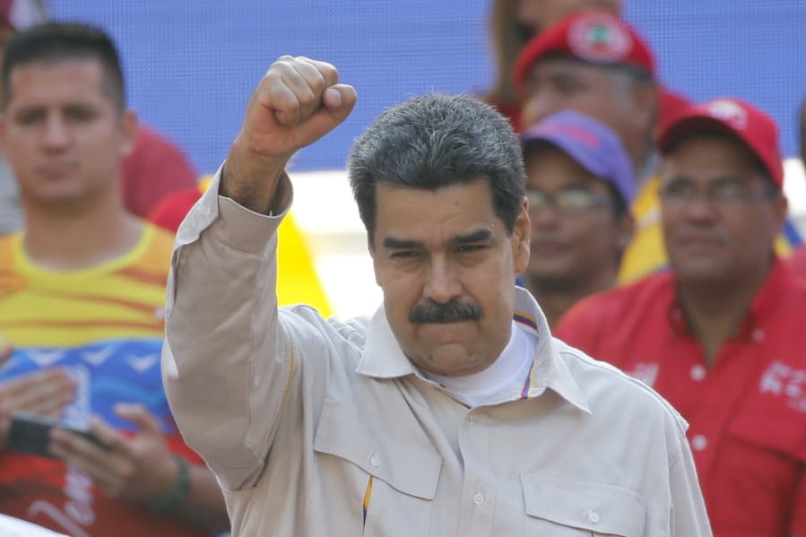 FILE - In this April 6, 2019 file photo, Venezuela’s President Nicolas Maduro raises his fist to supporters rallying at the presidential palace in Caracas, Venezuela. The Associated Press has learned on Saturday, June 15, 2019, that major European nations are considering imposing sanctions on Maduro and several top officials for their recent crackdown on political opponents.