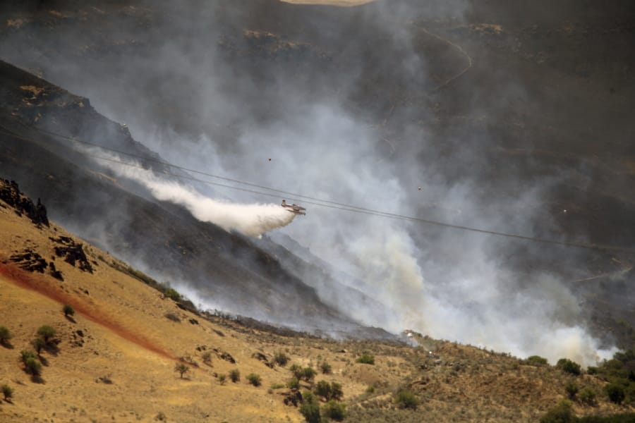 A plane drops water on the Substation fire July 19, 2018, near where the Deschutes and Columbia rivers meet along Interstate 84 and State Route 15 east of Portland.