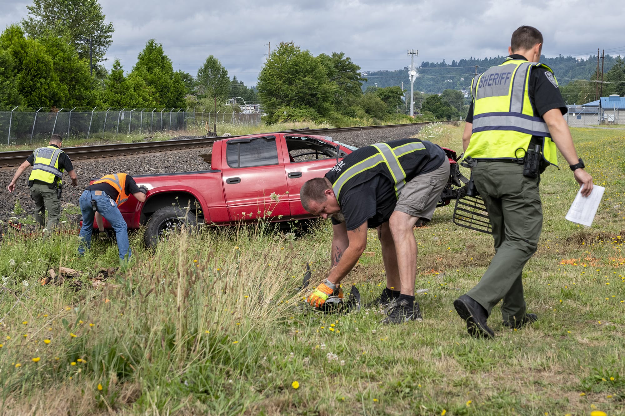 Law enforcement officers partner with members of Burlington Northern Santa Fe Railway to clear debris after a truck was struck by a train at the Whitney Street crossing in Washougal on July 15.