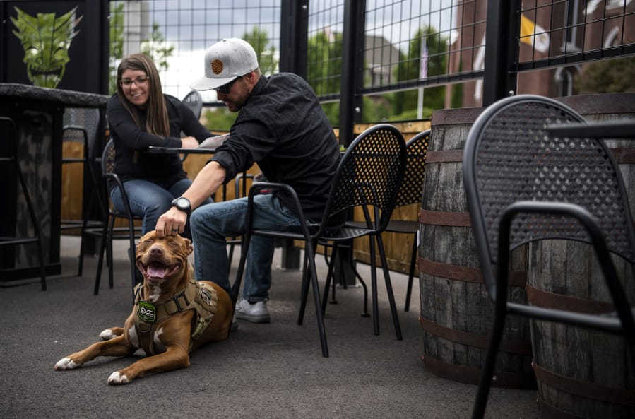 Bernadette Pye, her husband Andy and their red nose pitbull, Suntwo, enjoy an evening at Heathen Brewing Feral Public House in Vancouver. Clark County Public Health has created a variance to Washington’s food code that allows dogs on outdoor spaces at restaurants. Heathen and Loowit Brewing are the only restaurants to receive variances so far.