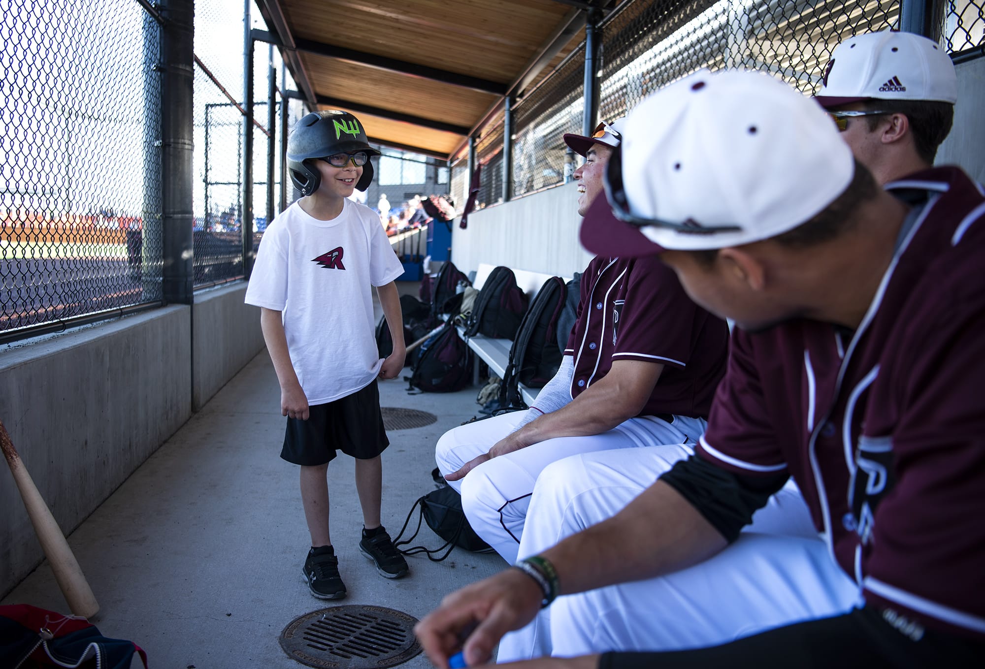 Aidan Deeney of Vancouver, 11, chats with the Raptors players before the game against the Cowlitz Black Bears at the Ridgefield Outdoor Recreation Complex on Friday night, July 12, 2019. Two local kids get to help out the team each game by retrieving balls and bats from the field.