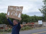 Mike King holds up a sign along Northwest 43rd Avenue in Camas on Wednesday during a protest by the Camas Tree Protectors. The new group hosted the event to protest a developer cutting down nearly 80 trees, some of which can be seen across the street.