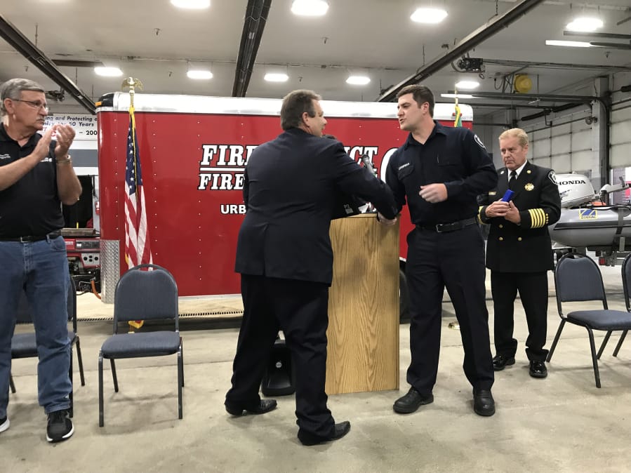 Clark County Fire District 6 Firefighter Tony Lothspeich prepares to receive an award from Board of Fire Commissioners Chair Casey Collins on Tuesday at Station 61 in Hazel Dell.