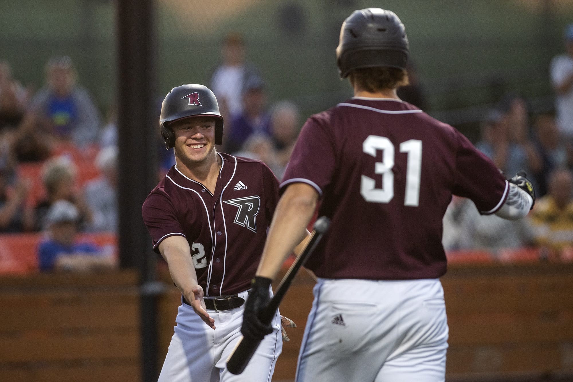 Raptors Justin Boyd (2) and Michael Hicks (31) high five after Boyd makes a run during Friday night's game against the Pickles at the Ridgefield Outdoor Recreation Complex on July 19, 2019. The Raptors won 5-2.