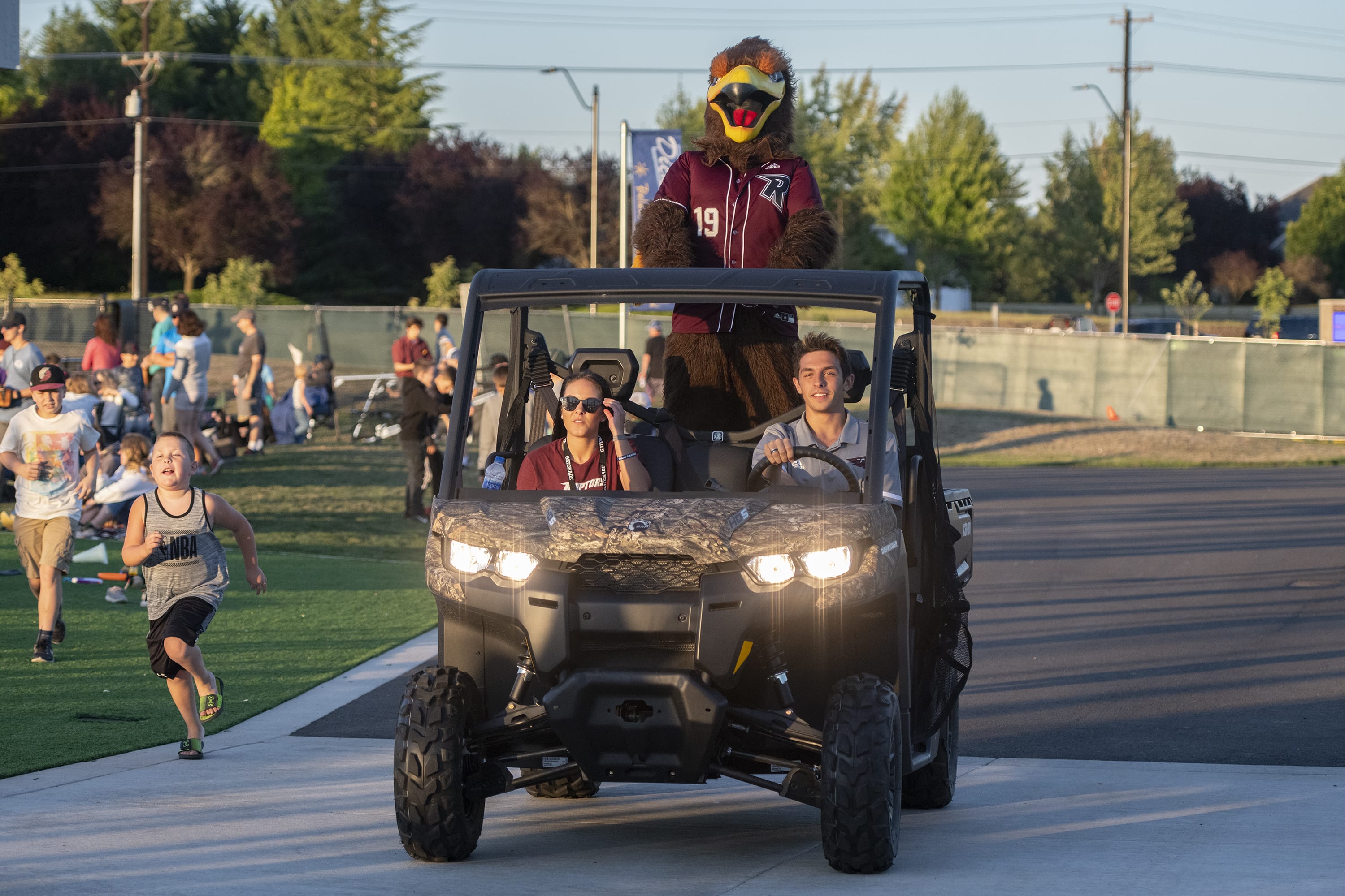 Eight-year-old Trace Musgrave, left, chases Rally the Raptor at the Ridgefield Outdoor Recreational Complex on Friday evening, July 19, 2019. The Raptors defeated the Pickles 5-2.