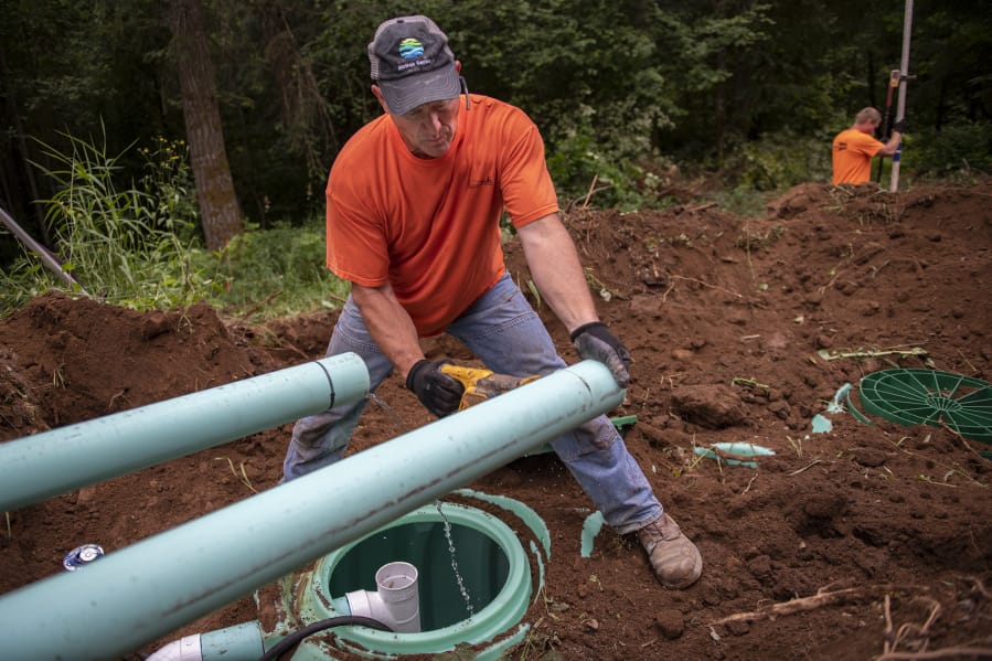 Pete Roberts, foreground, saws into PVC pipe during the installation of a septic tank at a home in Amboy last week. Roberts has owned Bloomquist Septic Inspections since 1997, after spending more than 10 years in the military. He never set out to work in the septic business, and acknowledges that it’s a dirty job.