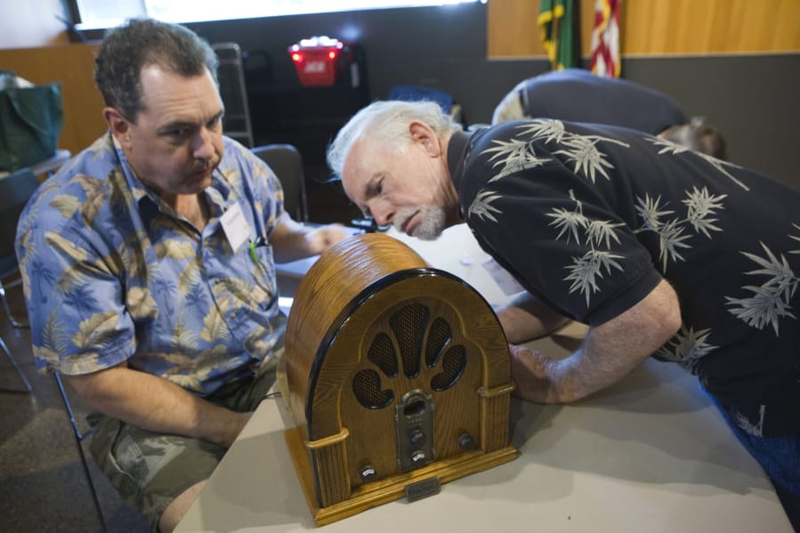 Volunteers Neil Sedell and Dave Meigs look at an old radio as they attempt to repair it during a 2017 event at the Vancouver Community Library.