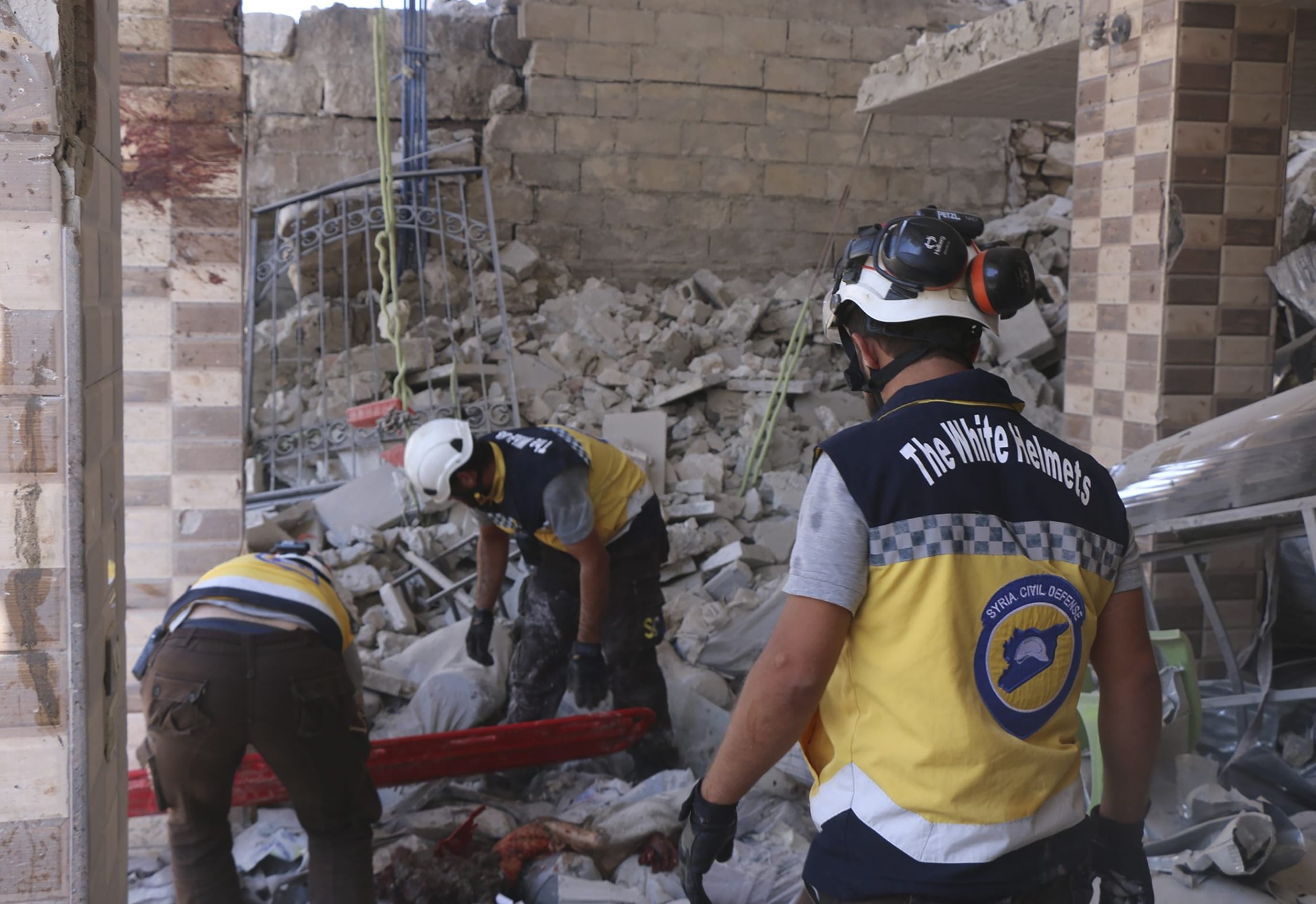 This photo provided by the Syrian Civil Defense White Helmets, which has been authenticated based on its contents and other AP reporting, shows Syrian White Helmet civil defense workers search for victims from under the rubble of a destroyed building that hit by Syrian government and Russian airstrikes, in the northern town of Maaret al-Numan, in Idlib province, Syria, Monday, July 22, 2019. Syrian opposition activists say an airstrike on a busy market in a rebel-held town in northwestern Syria has killed at least 16 people.