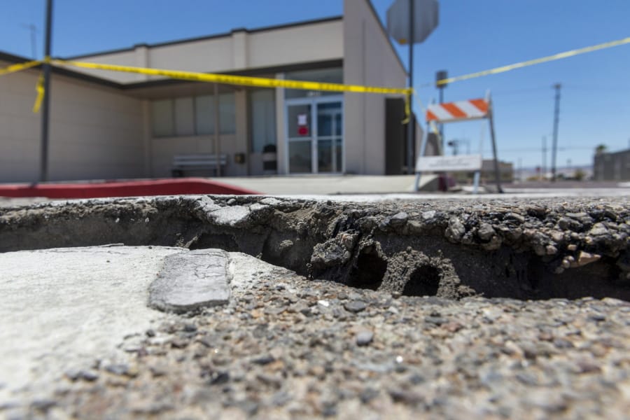 Damaged pavement from an earthquake surrounds the Searle Valley Domestic Water company in Trona, Calif., on Wednesday, July 10, 2019. The water company, the U.S. Post office building and a local restaurant were among the commercial buildings deemed unfit for occupancy after recent earthquakes. Residents of the little community of Trona gathered at a town hall Wednesday to hear officials give updates on the recovery.