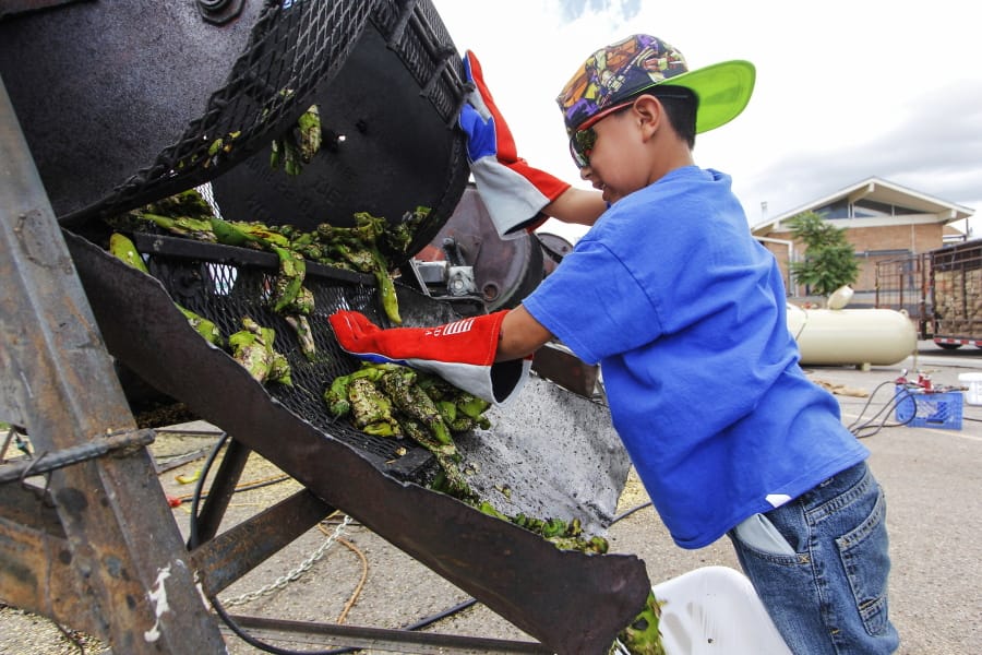 FILE - In this Aug. 9, 2017, file photo, Chris Duran Jr, 7 helps roast green chile with his family outside the Big Lots in Santa Fe, N.M. A hybrid version of a New Mexico chile plant has been selected to be grown in space as part of a NASA experiment, officials recently announced.