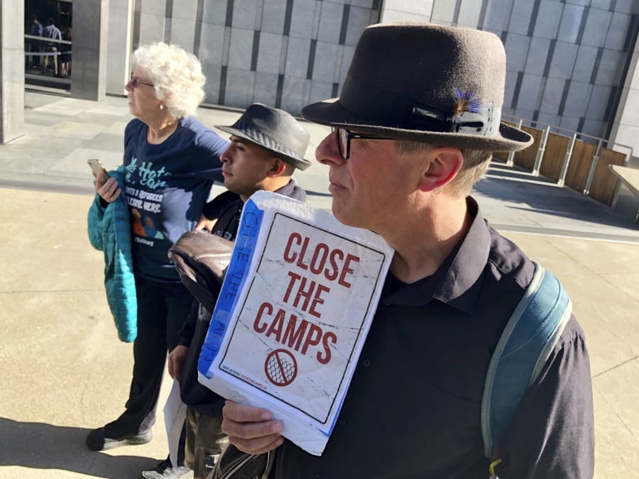 Ben Terrall holds a protest sign that reads “Close The Camps” outside of the San Francisco Federal Courthouse on Wednesday, July 24, 2019 in San Francisco, Calif. A federal judge said Wednesday that the Trump administration can enforce its new restrictions on asylum for people crossing the U.S.-Mexico border while lawsuits challenging the policy play out.