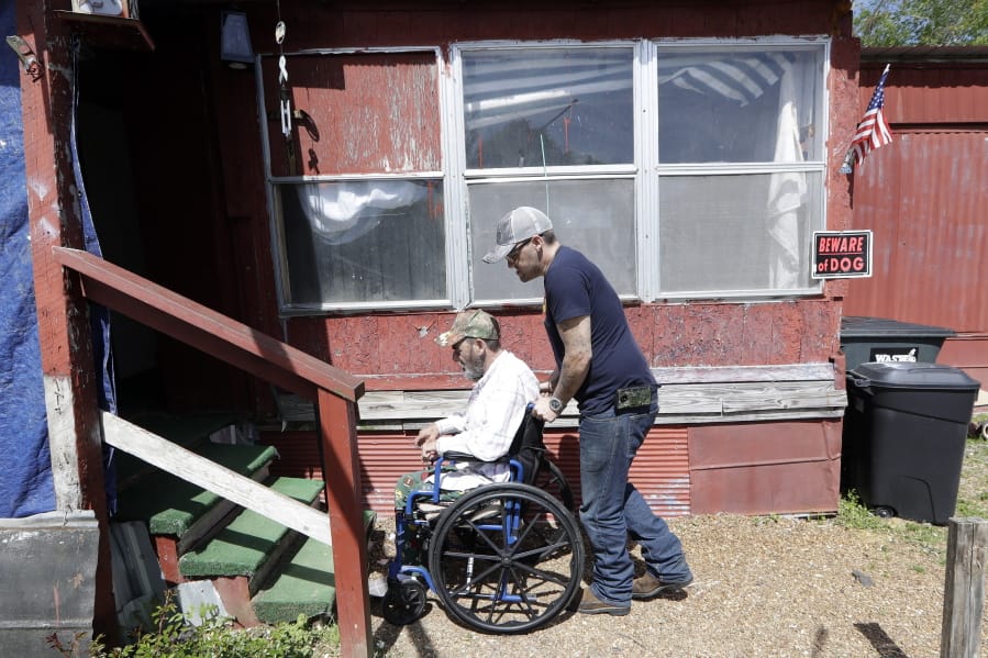 Johnny Gibbs helps his disabled father, Mike, 65, into their home April 16 in Liberty, Tenn. After getting some traffic tickets he couldn’t pay, he became caught a in spiral of fees, fines and debt that left him unable to afford a driver’s license.