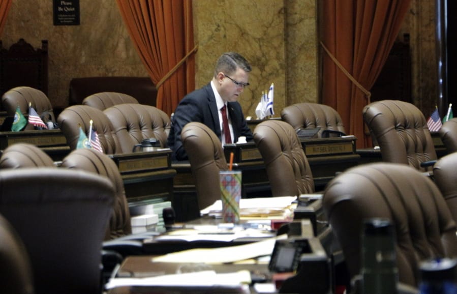 FILE - In this April 26, 2019 fIle photo, Republican state Rep. Matt Shea sits at his desk on the House floor in Olympia, Wash. The Washington state House has hired a firm to investigate whether Shea has engaged in, planned or promoted political violence and to determine the extent of his involvement with groups or people involved with such activities. Shea came under fire following reports in The Guardian of contents of internet chats from 2017 involving Shea and three other men proposing to confront “leftists” with a variety of tactics, including violence, surveillance and intimidation.