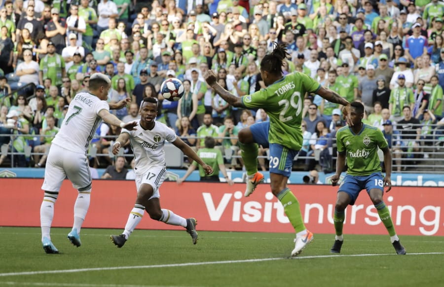 Portland Timbers forward Brian Fernandez, left, kicks a goal as forward Jeremy Ebobisse, second from left, as Seattle Sounders’ defenders Roman Torres (29) and Kelvin Leerdam, right, look on during the first half of an MLS soccer match, Sunday, July 21, 2019, in Seattle. (AP Photo/Ted S.