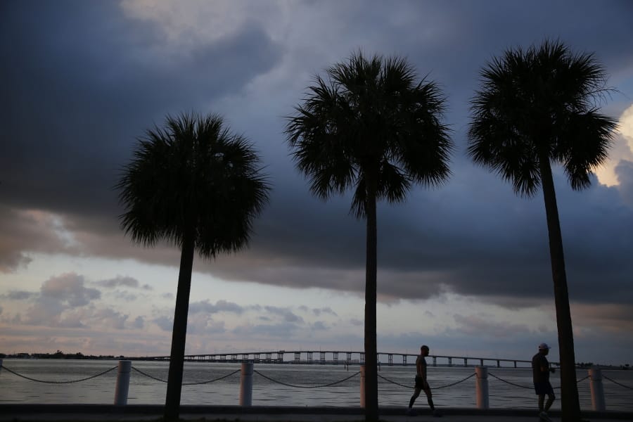In this June 4, 2019, photo two people walk along the water in the early morning sunrise near downtown Miami in Key Biscayne, Fla. Some debts that bring the promise of opportunity, like student loans or mortgages, might seem “good,” but that’s not always the case. And having credit card debt isn’t always bad. What makes debt “good” or “bad” depends on how it fits into your overall financial picture.