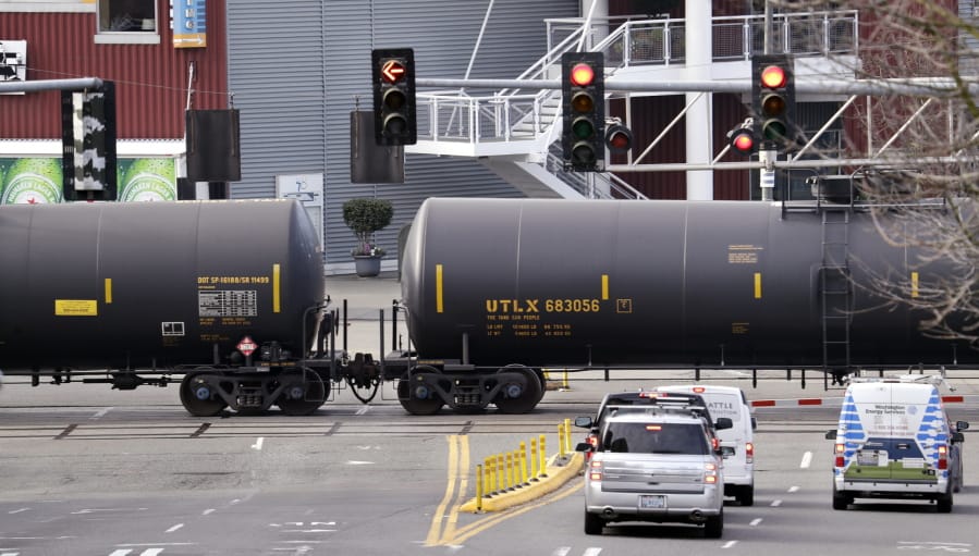 Automobile traffic waits in February 2018 at a train crossing as train cars that carry oil are pulled through downtown Seattle.