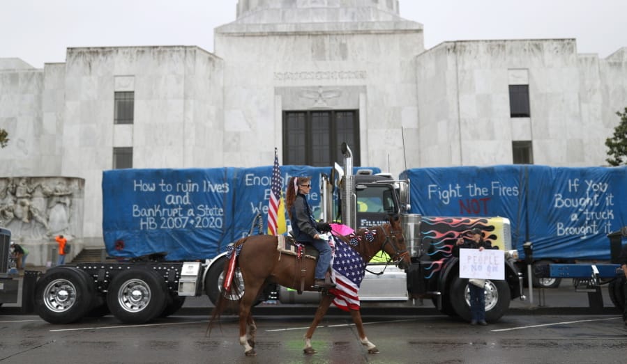 A woman rides a horse as truckers and loggers opposed to a carbon-capping bill hold a rally on June 27 at the Capitol in Salem, Ore.