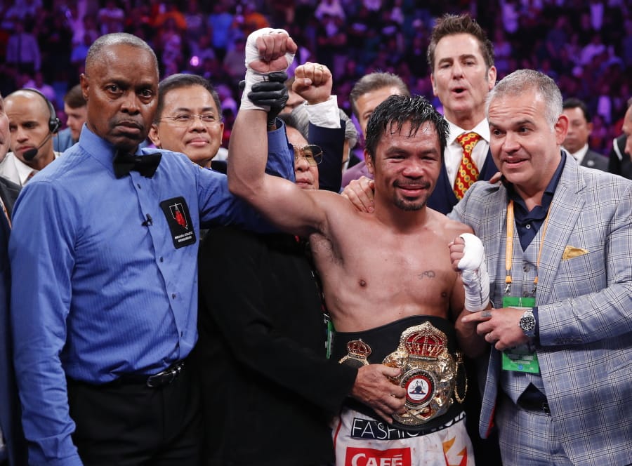 Manny Pacquiao, center, reacts as referee Kenny Bayless holds up his hand signaling his victory over Keith Thurman in a welterweight title fight Saturday, July 20, 2019, in Las Vegas. Pacquiao won by split decision.