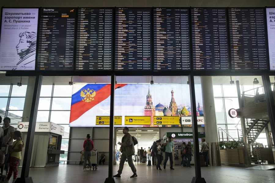 Passengers walk past a departure board at Sheremetyevo international airport in Moscow, Russia, Monday, July 8, 2019. The Russian government’s ban on direct flights between Russia and Georgia came into effect on Monday, affecting thousands of travelers.
