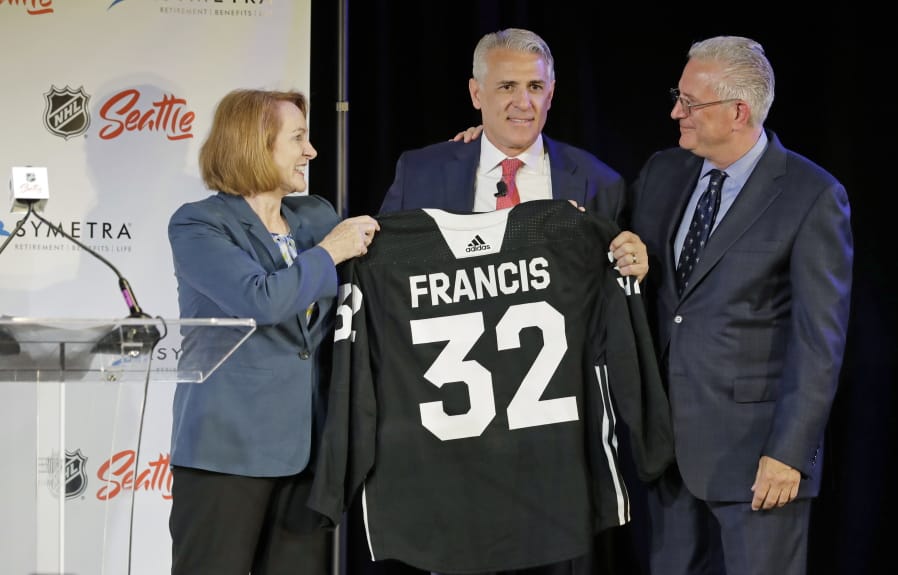 Ron Francis, center, is presented with a hockey jersey by Seattle Mayor Jenny Durkan, left, as Seattle Hockey Partners CEO Tod Leiweke looks on Thursday, July 18, 2019, in Seattle, as Francis is introduced as the first general manager for Seattle’s yet-to-be-named NHL expansion team. Francis, a Hall of Famer and a two-time Stanley Cup winner, will have complete control of operations under Leiweke when the team debuts in 2021. (AP Photo/Ted S.