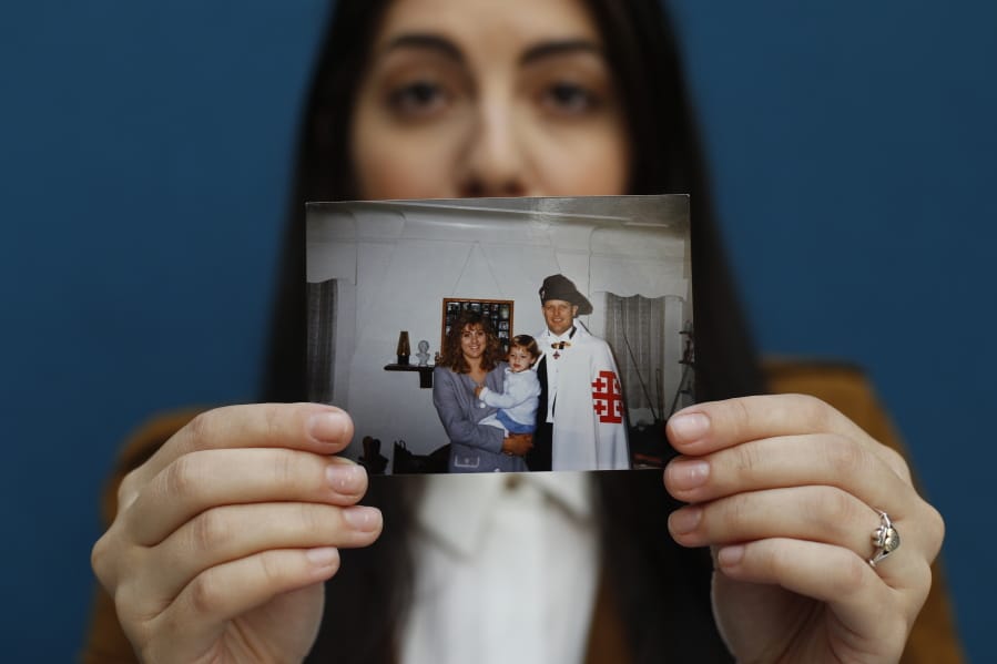 Mary Rose Maher, the daughter of Opus Bono Sacerdotii co-founder Joe Maher, holds a photo from her childhood with her parents in Detroit, Wednesday, June 12, 2019. Opus Bono’s finances came under scrutiny after authorities were contacted by a once-loyal employee - Mary Rose - who began questioning the way money was spent.