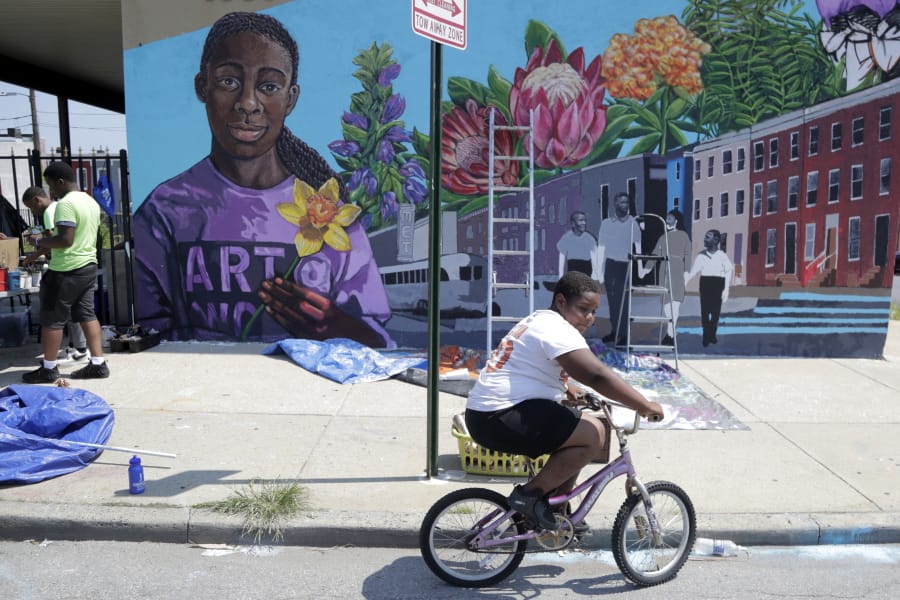 A boy rides his bicycle Monday, July 29. 2019 after volunteering to paint a mural outside the New Song Community Church in the Sandtown section of Baltimore. In the latest rhetorical shot at lawmakers of color, President Donald Trump over the weekend vilified Rep.