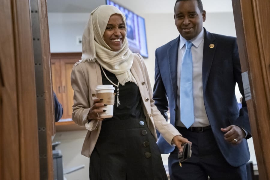 Rep. Ilhan Omar, D-Minn., a target of racist rhetoric from President Donald Trump, is joined at right by fellow freshman Rep. Joe Neguse, D-Colo., as she walks to her office following votes, at the Capitol in Washington, Thursday, July 18, 2019. (AP Photo/J.