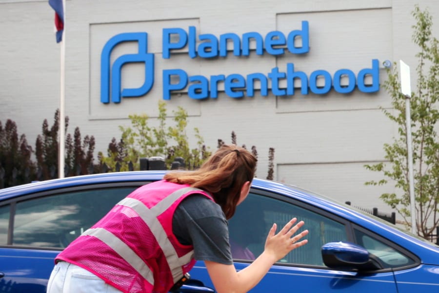Robert Cohen/St. Louis Post-Dispatch Ashlyn Myers of the Coalition for Life St. Louis, waves to a Planned Parenthood staff member June 28 in St. Louis, Mo. The Trump administration says its new regulation barring taxpayer-funded family planning clinics from referring women for abortions is taking effect immediately.