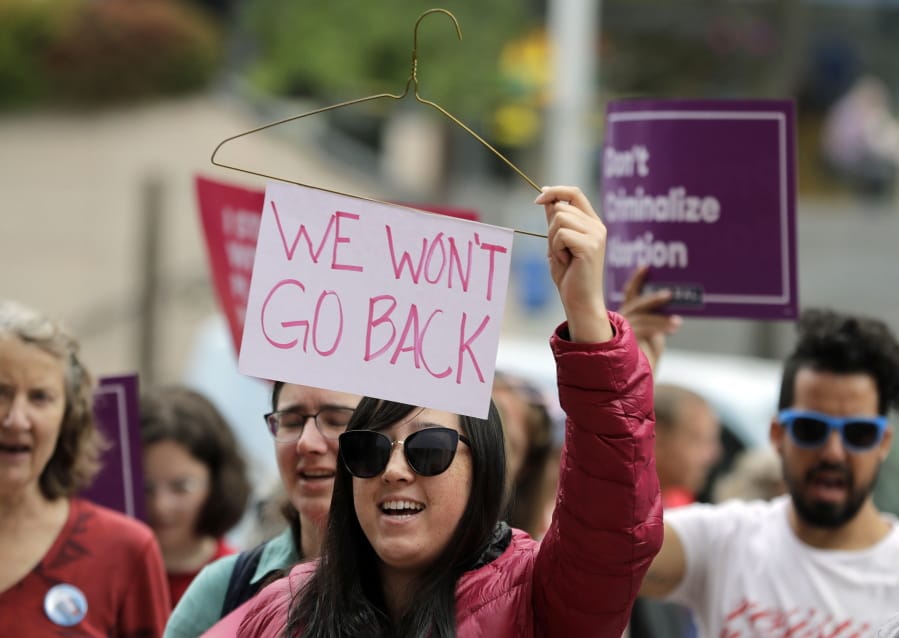 Hillary Namba, of Seattle, holds a wire coat hanger and a sign that reads “We Won’t Go Back” during a protest on July 10, 2018, in Seattle. Trump administration rules imposing additional hurdles for low-income women seeking abortions are on hold once again. Ted S.