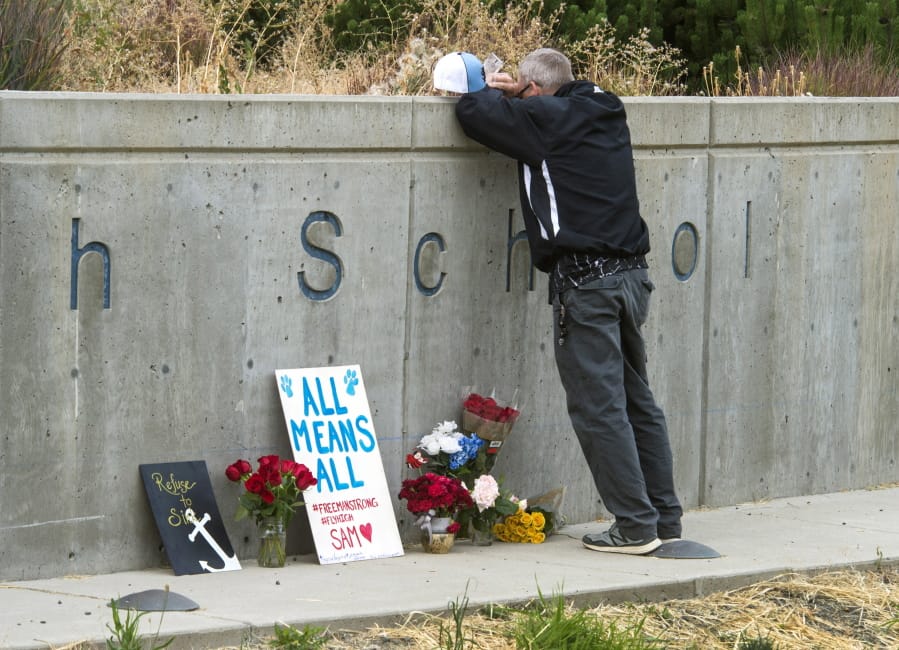 Freeman High School assistant football coach Tim Smetana grieves Sept. 14, 2017, after he placed roses at a memorial following a shooting at the school in Rockford, south of Spokane.
