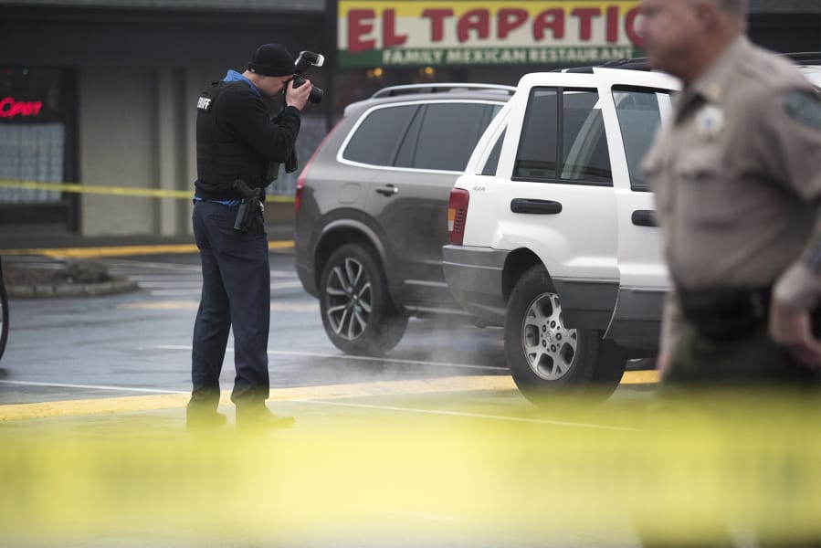 A Clark County Sheriff’s investigator photographs the car of a shooting victim at Pacific 63 Center in Hazel Dell on Dec. 10, 2018.