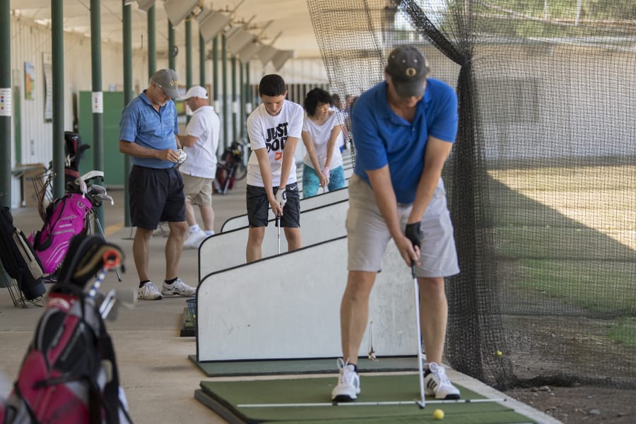 A crowd of golfers including Ridgefield resident Zac Warren, 15, center in white T-shirt, work on their swing during a busy summer afternoon at Vanco Golf Range.