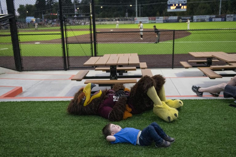 Rally, top, and Colin Jackson, 2, bottom, rest on the ground during the Raptors vs. Elks game at the Ridgefield Outdoor Recreation Complex on Friday evening, August 9, 2019.