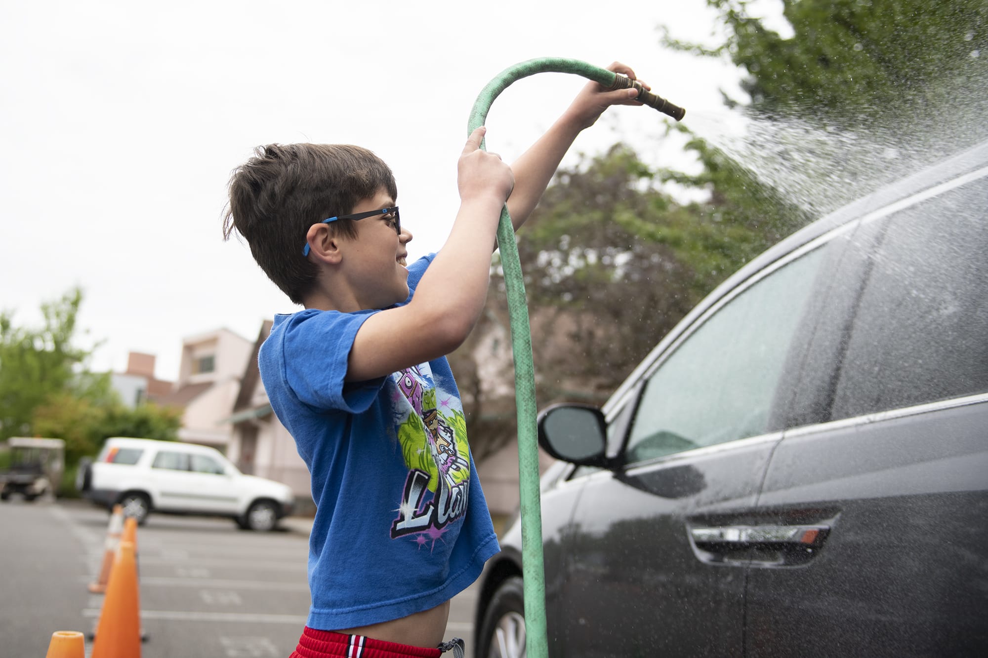 Eight-year-old Eli Bernardi of Ridgefield rinses off his dad's car during the Bottom Half Car Wash at Clark College's Child and Family Studies building on Thursday morning.