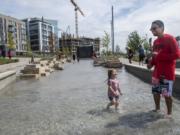 Adaline Sokol, 2, left, and Gage Marshall splash in the new Columbia River water feature Friday afternoon at the Waterfront Vancouver development. The piece opened to the public Friday morning, just in time for passersby to cool their feet in the late-summer heat.